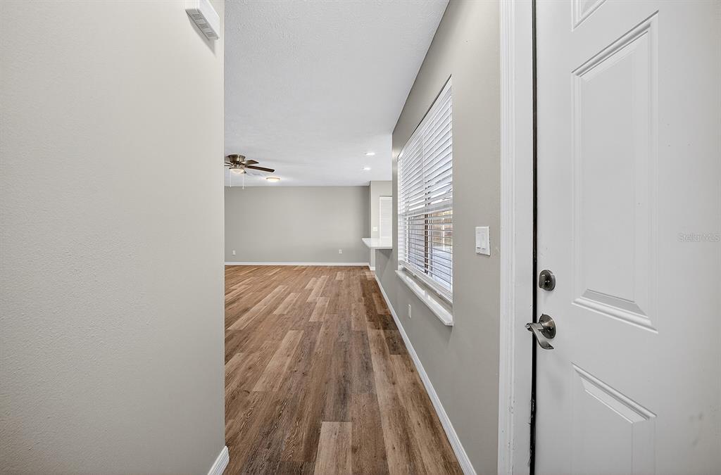 An entryway leads into a living area with wood-look flooring and a ceiling fan — 2948 TANGERINE COURT, LEESBURG, FL
