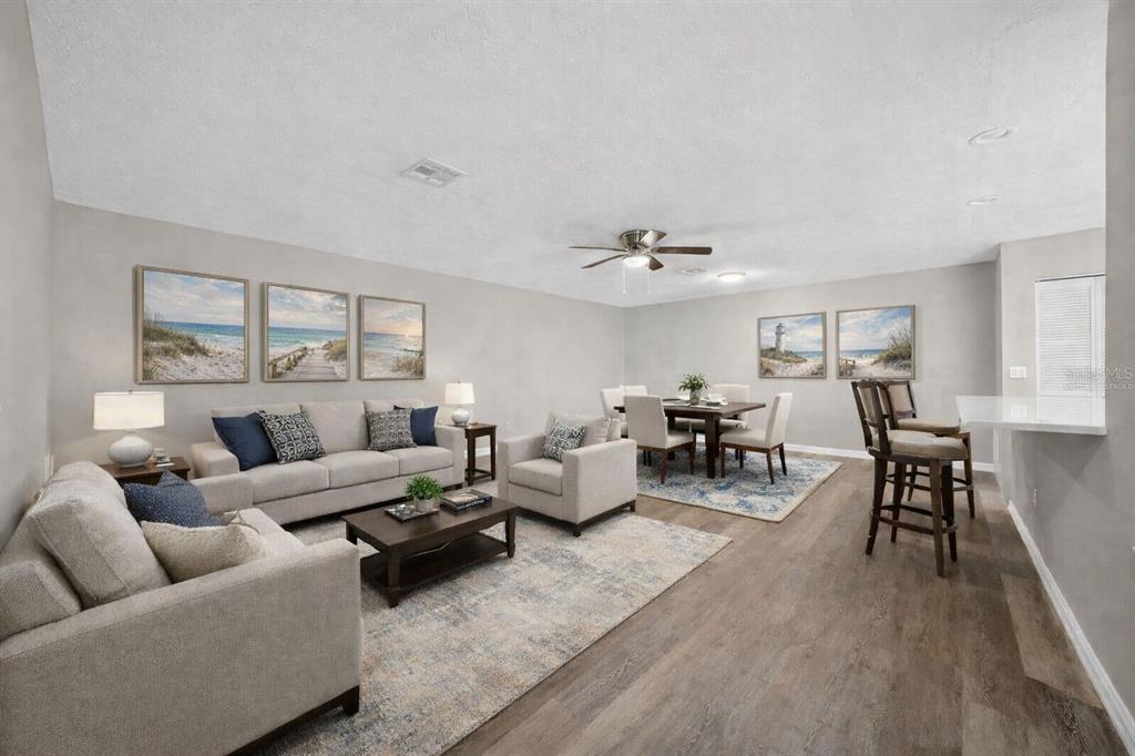 A living and dining area with neutral furniture, wood-look flooring, and coastal wall art — 2948 TANGERINE COURT, LEESBURG, FL