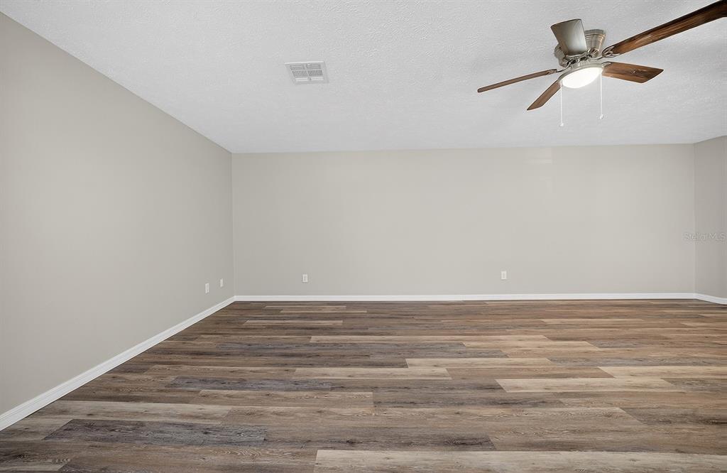 An empty room with light gray walls, wood-look flooring, and a ceiling fan — 2948 TANGERINE COURT, LEESBURG, FL