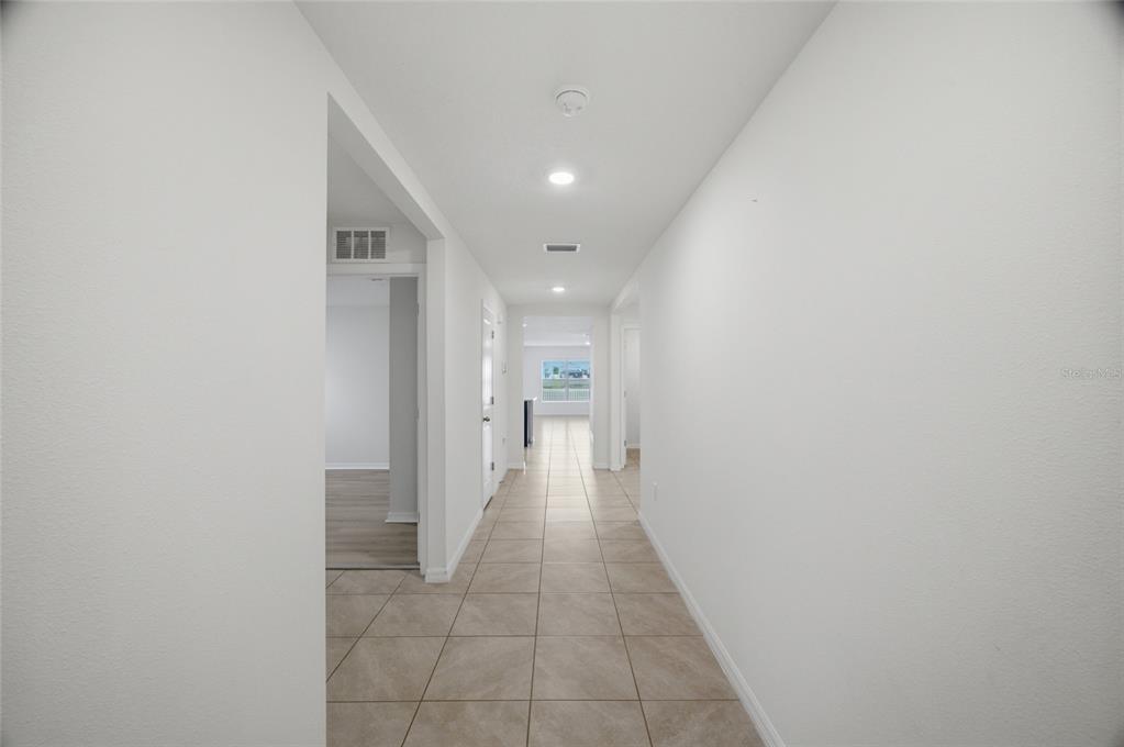 A tiled hallway leads toward an open living area with a window in the distance — 2812 GUMBO LIMBO DRIVE, WIMAUMA, FL