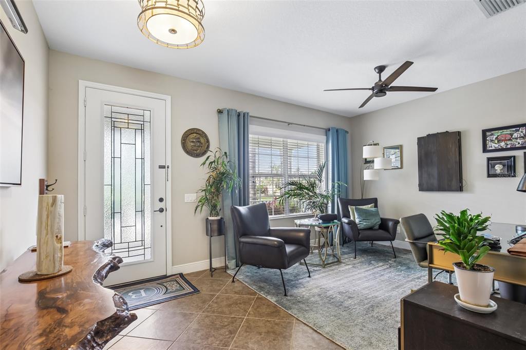 A bright home office features a glass-paneled front door, tile flooring, and two leather armchairs — 12307 WHISPER LAKE DRIVE, BRADENTON, FL