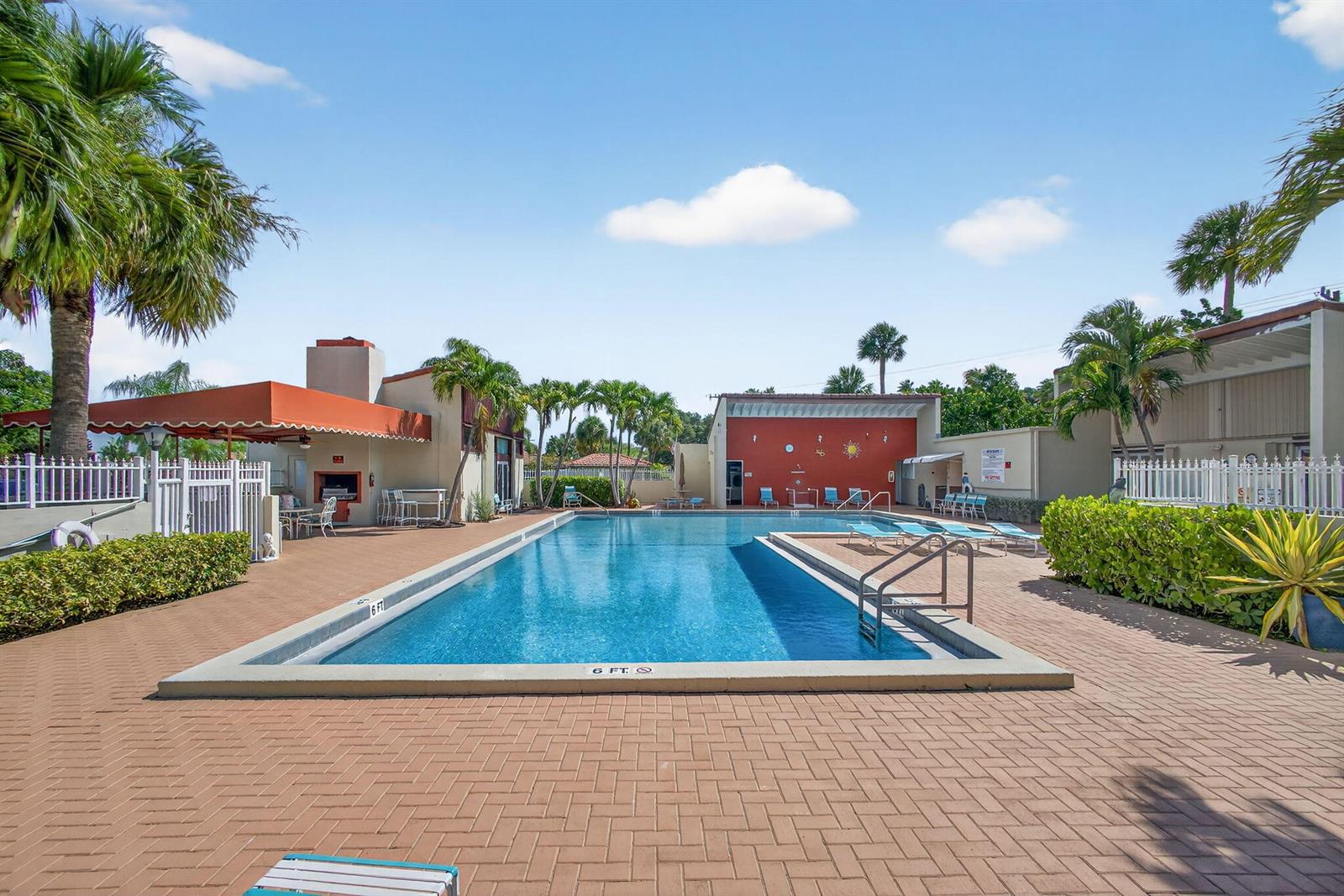 A rectangular swimming pool sits on a brick patio surrounded by palm trees and buildings — 2532 S Boundbrook Dr S # 102, Palm Springs FL 33406, PALM SPRINGS, FL