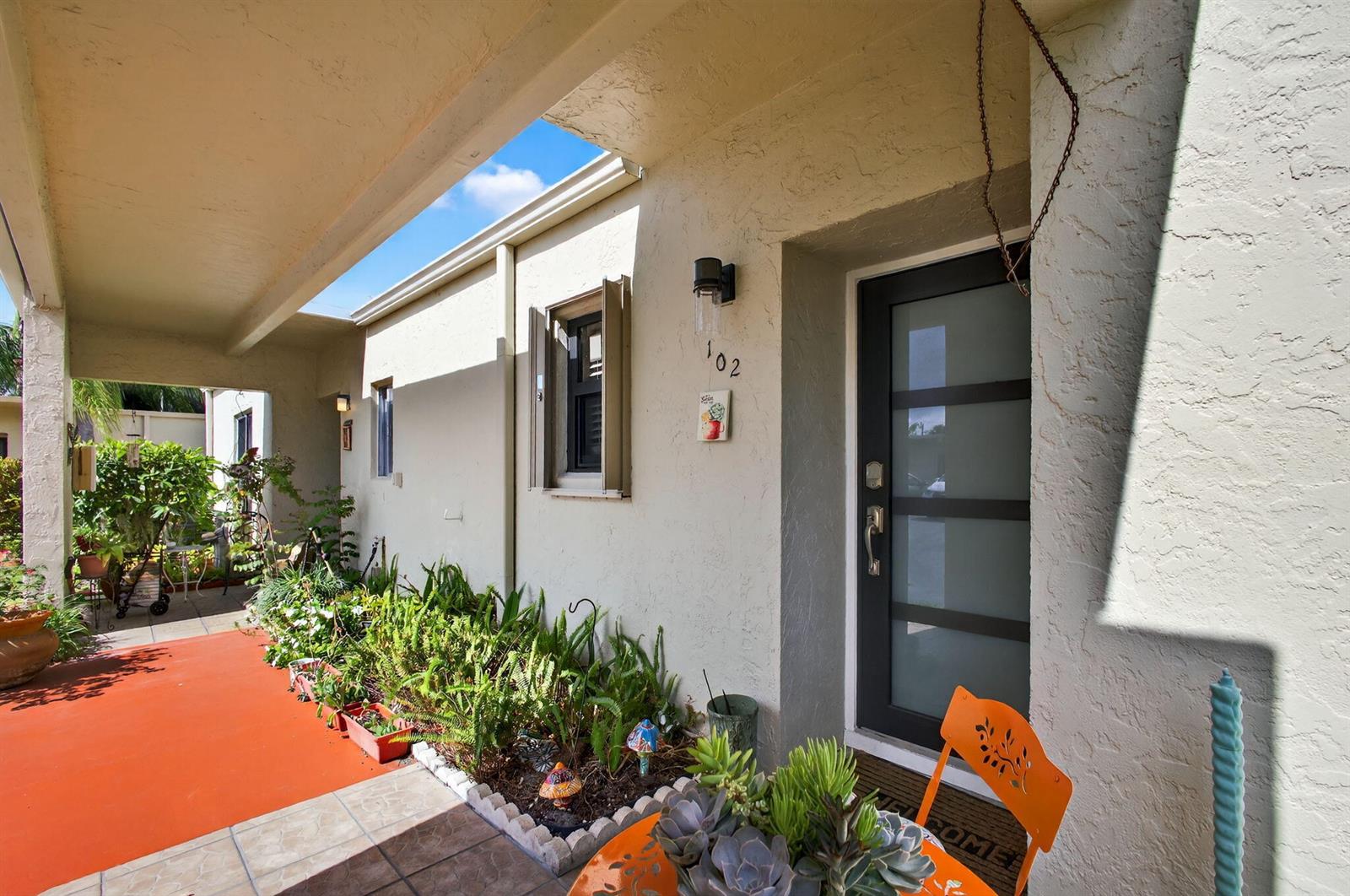 An exterior view of a home entrance with a covered porch, plants, and a door — 2532 S Boundbrook Dr S # 102, Palm Springs FL 33406, PALM SPRINGS, FL