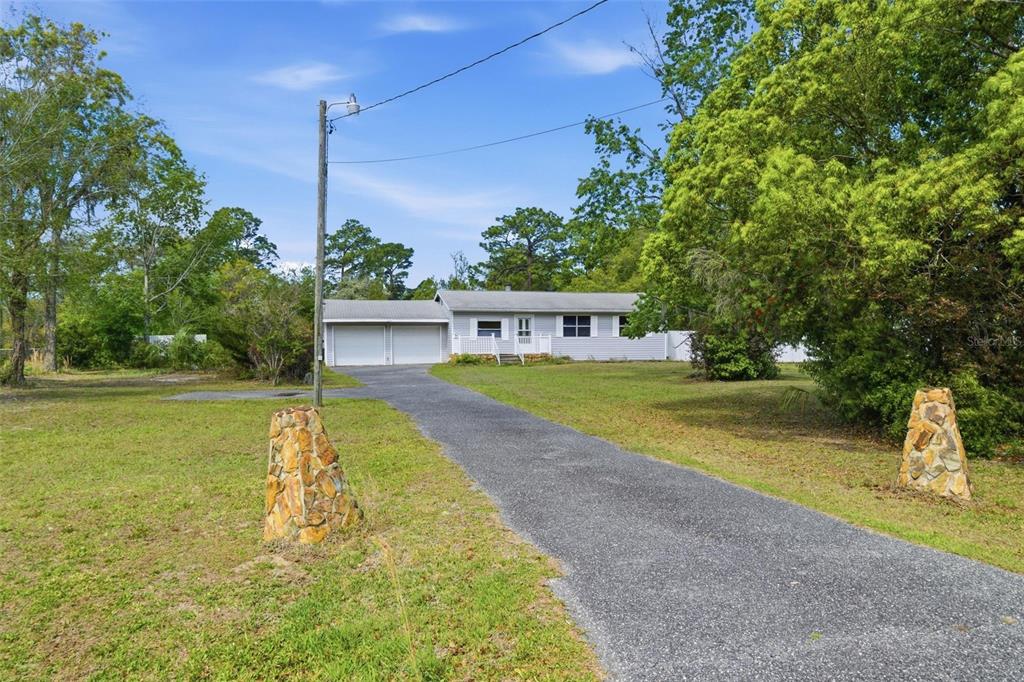 A single-story house with a two-car garage and a long driveway sits on a lot — 2670 S PINE RIDGE AVENUE, HOMOSASSA, FL