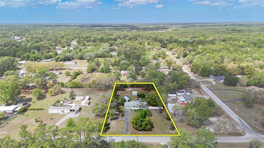 An aerial view shows a single-story house on a large, partially wooded residential lot — 2670 S PINE RIDGE AVENUE, HOMOSASSA, FL