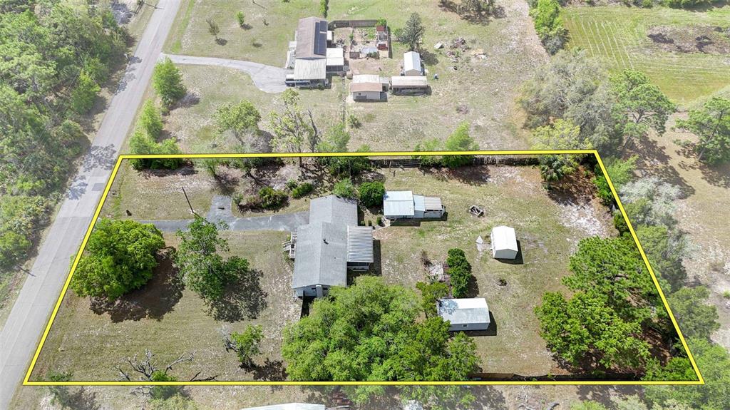 An aerial view shows a house with several outbuildings on a large, grassy, tree-lined lot — 2670 S PINE RIDGE AVENUE, HOMOSASSA, FL