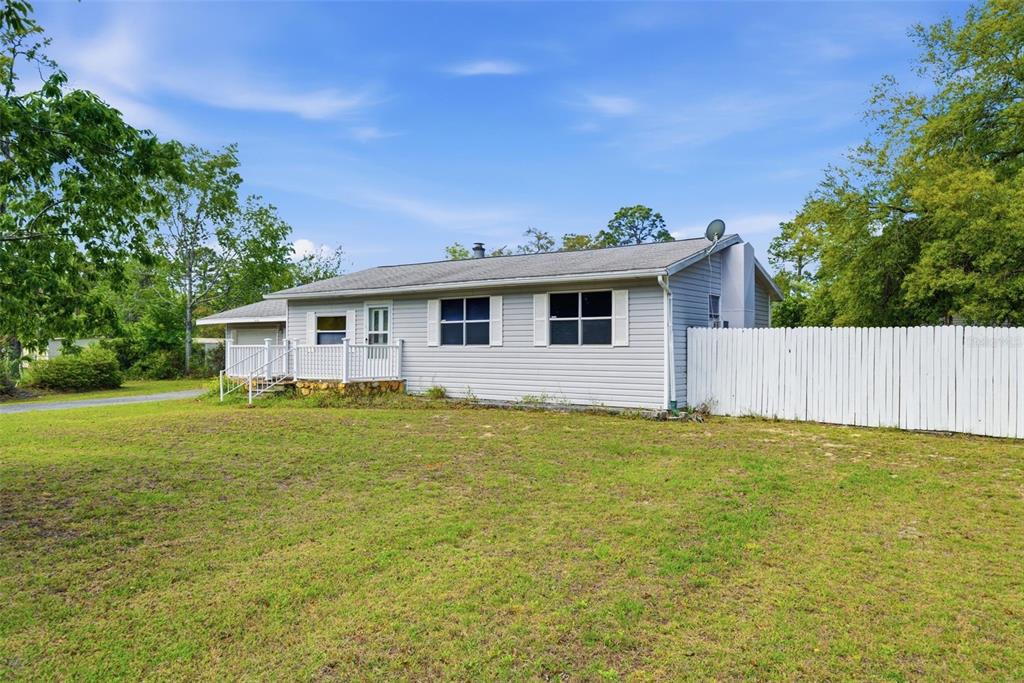 A single-story house with light gray siding, a white porch railing, and a white fence — 2670 S PINE RIDGE AVENUE, HOMOSASSA, FL