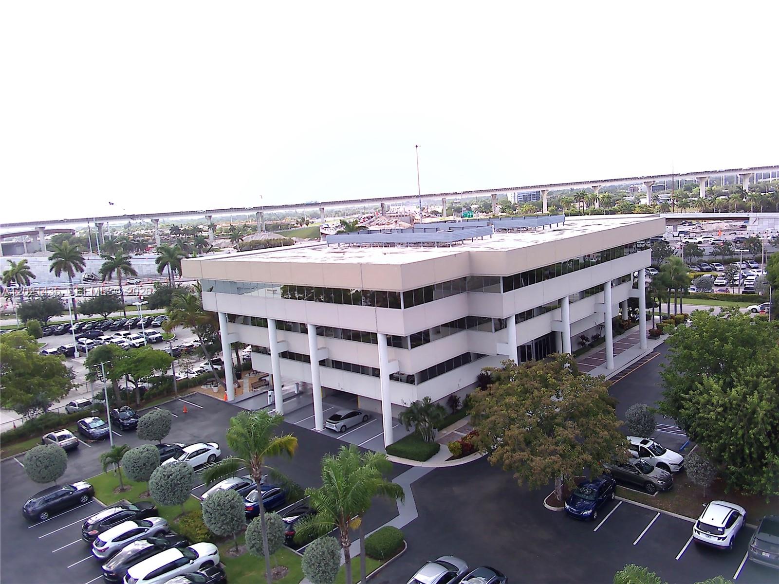 An aerial view of a multi-story office building with a parking lot and surrounding trees — 290 NW 165th St # 7, Miami FL 33169, MIAMI, FL