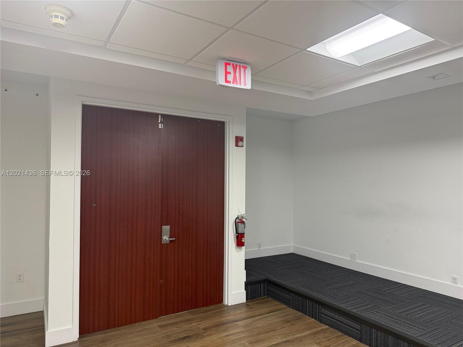 A room features double wood doors, a raised carpeted platform, and an exit sign — 290 NW 165th St # 7, Miami FL 33169, MIAMI, FL