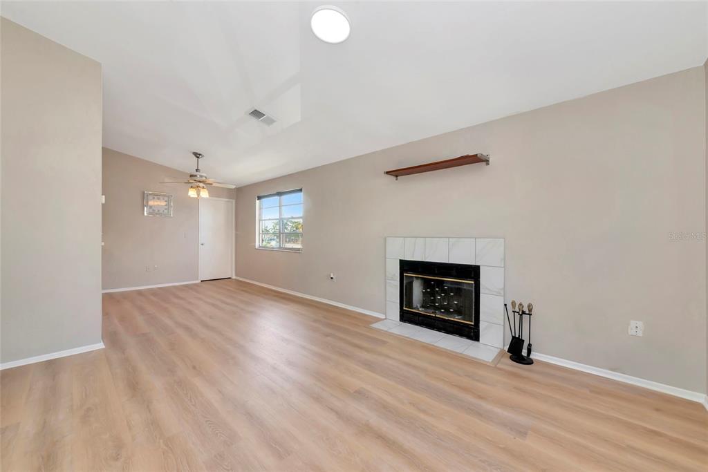 A living room features light wood-look flooring, a fireplace with white tile, and a ceiling fan — 3880 59TH AVENUE W UNIT 4196, BRADENTON, FL