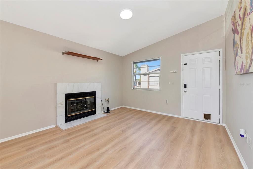 A living room features light wood-look flooring, a fireplace with white tile, and a front door — 3880 59TH AVENUE W UNIT 4196, BRADENTON, FL