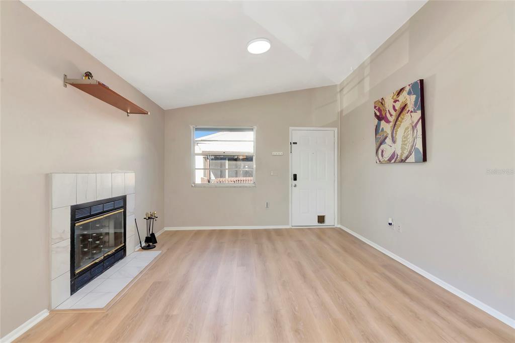 A living room features light wood-look flooring, a white fireplace, a window, and a door — 3880 59TH AVENUE W UNIT 4196, BRADENTON, FL
