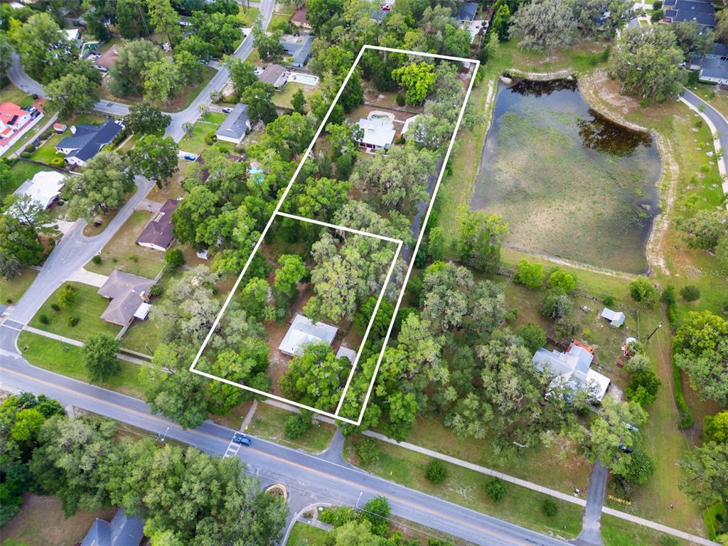 An aerial view shows two adjacent residential lots with houses and trees near a pond — 2604 * NW 31ST AVENUE, GAINESVILLE, FL