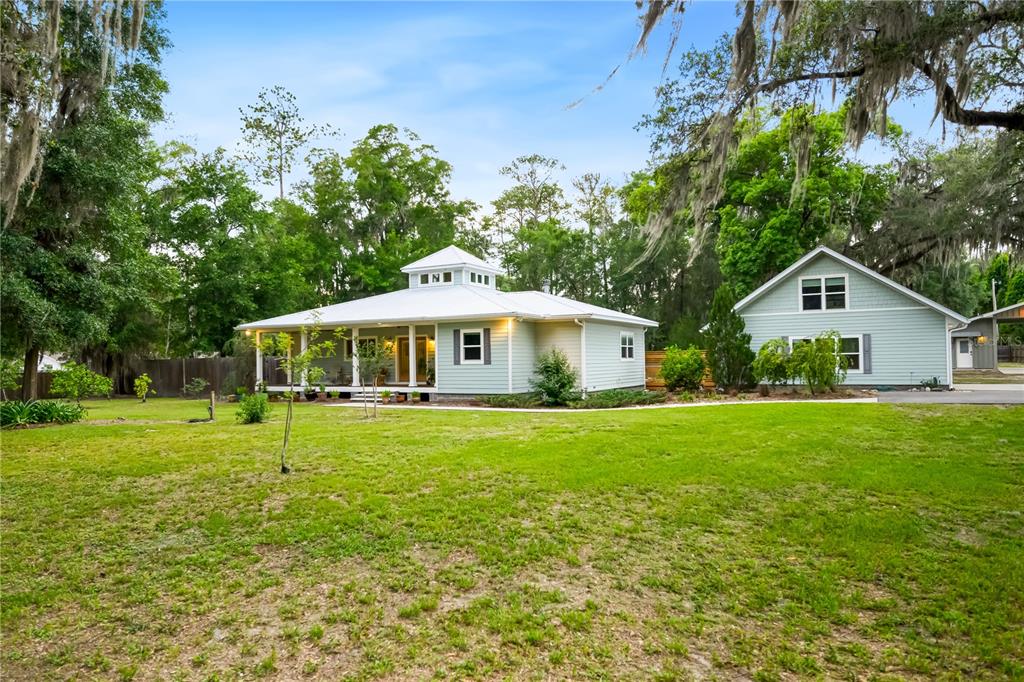 A light green house with a white metal roof and a detached garage sits on grass — 2604 * NW 31ST AVENUE, GAINESVILLE, FL