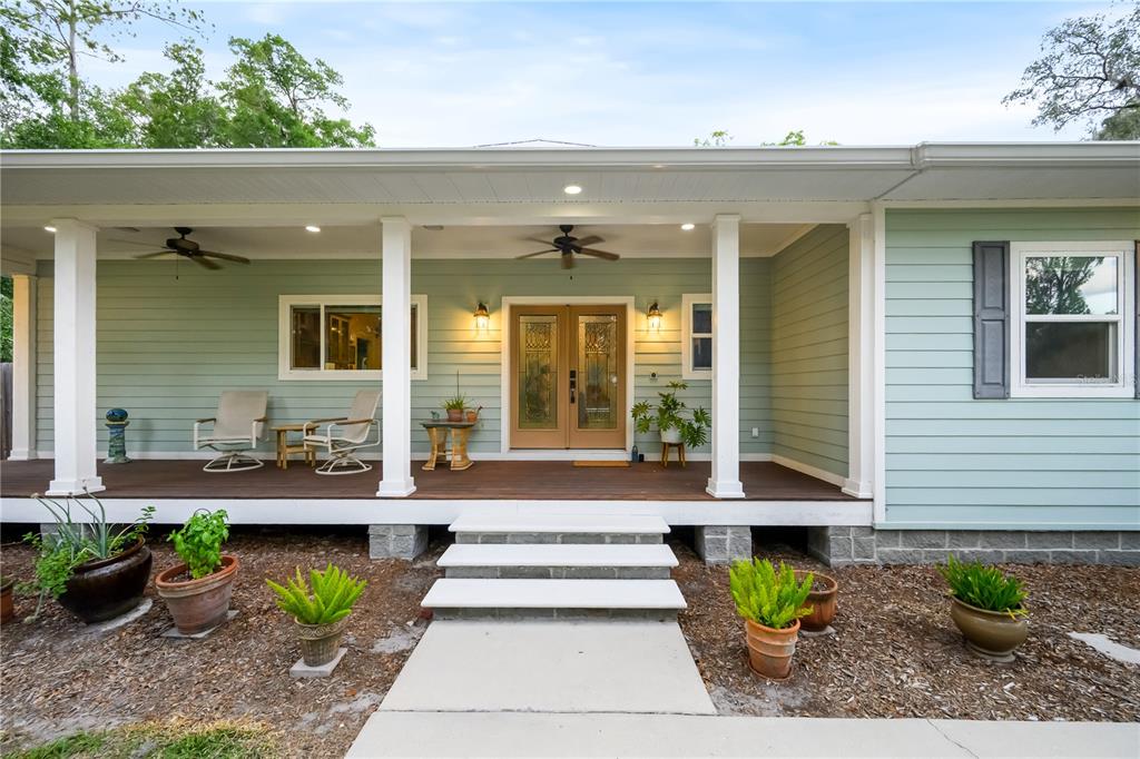 A light green house with a covered wooden porch, double front doors, and concrete steps — 2604 * NW 31ST AVENUE, GAINESVILLE, FL