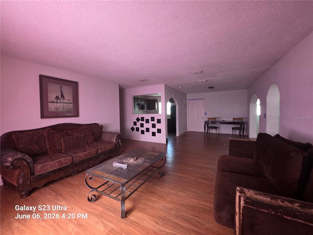 A living room features wood-look flooring, two brown sofas, a coffee table, and arched doorways — 2086 MARTIN LUTHER KING JR BOULEVARD, BARTOW, FL