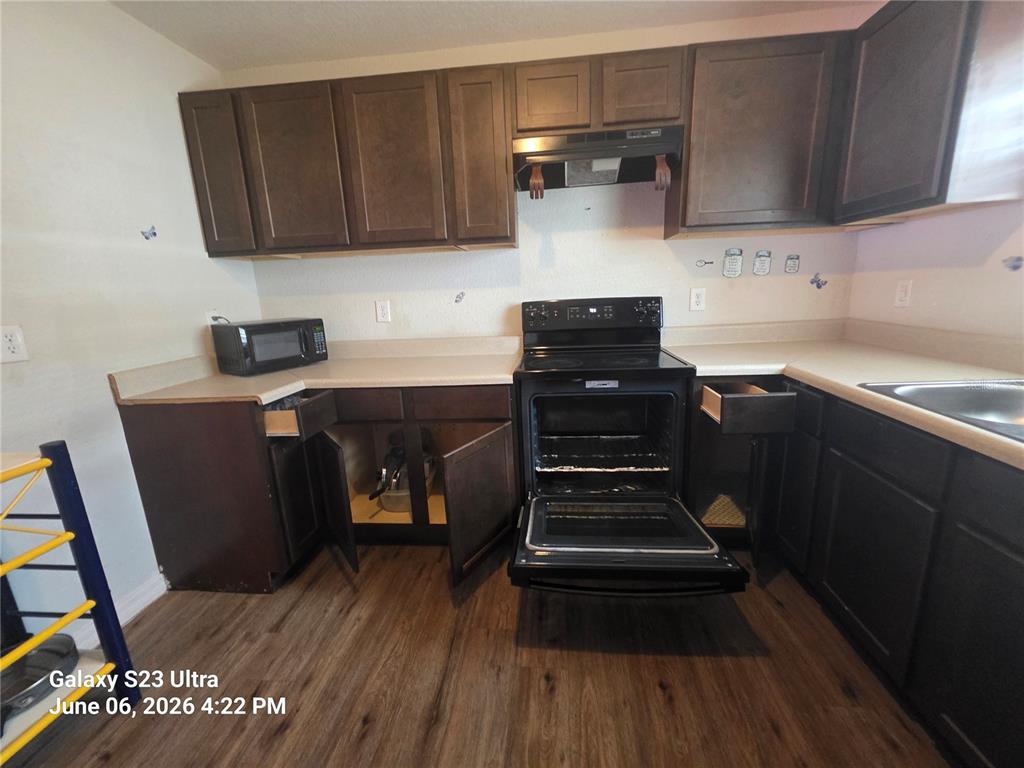 A kitchen features dark wood cabinets, a black stove, and light-colored countertops — 2086 MARTIN LUTHER KING JR BOULEVARD, BARTOW, FL