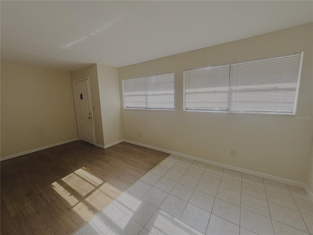 A room with a mix of wood-look flooring and white tile, two windows, and a door — 1915 SW 70 TERRACE UNIT C, GAINESVILLE, FL