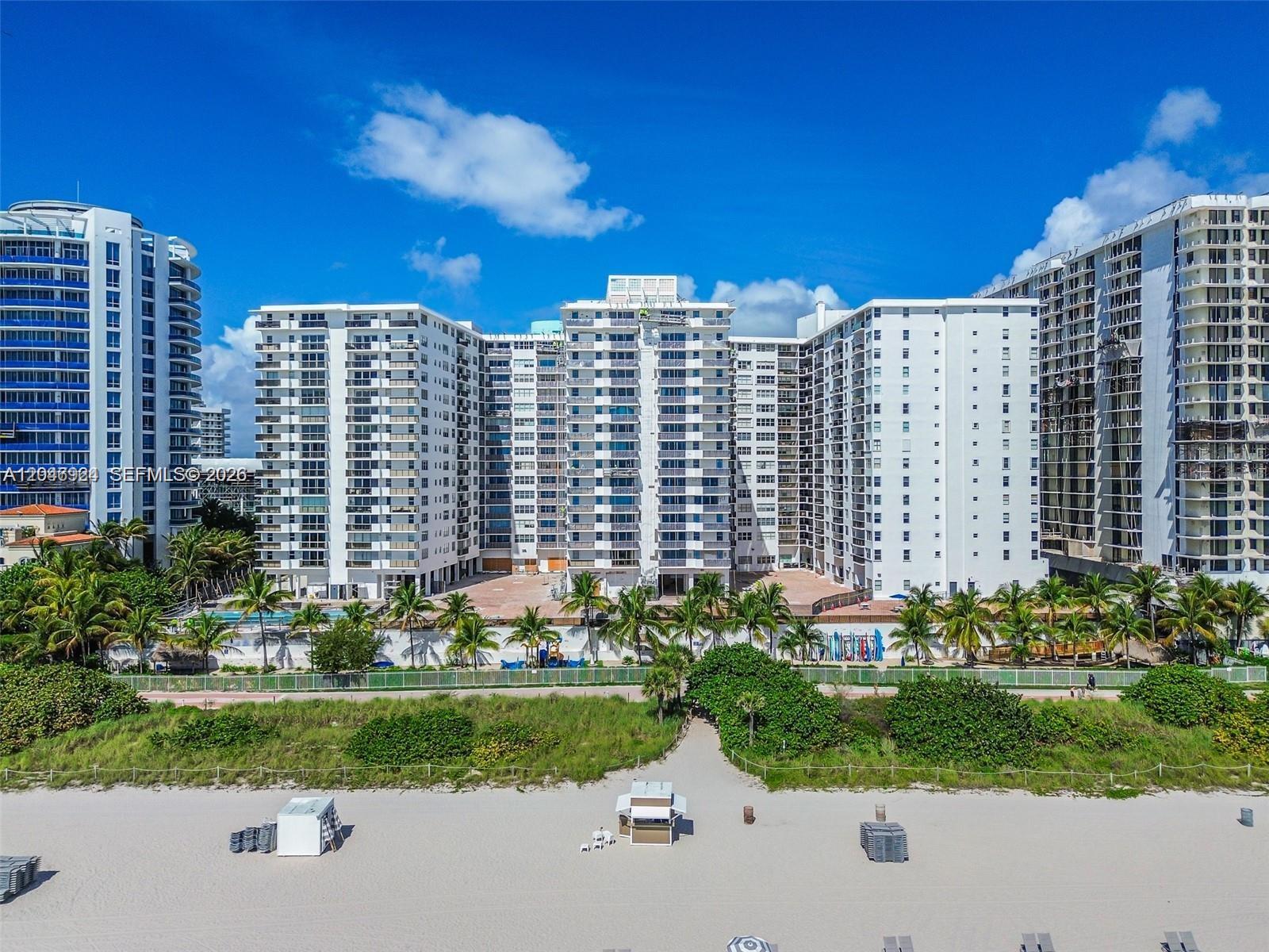A living room with a large television, a leather sofa, and a view of the ocean — 6039 Collins Ave # 619, Miami Beach FL 33140, MIAMI BEACH, FL