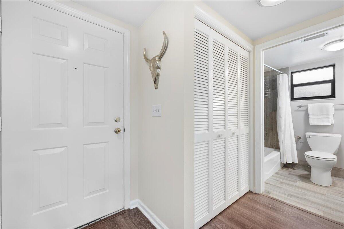 A white door and louvered closet doors lead to a bathroom with a toilet and shower — 11863 Wimbledon Circle # 524, Wellington FL 33414, WELLINGTON, FL