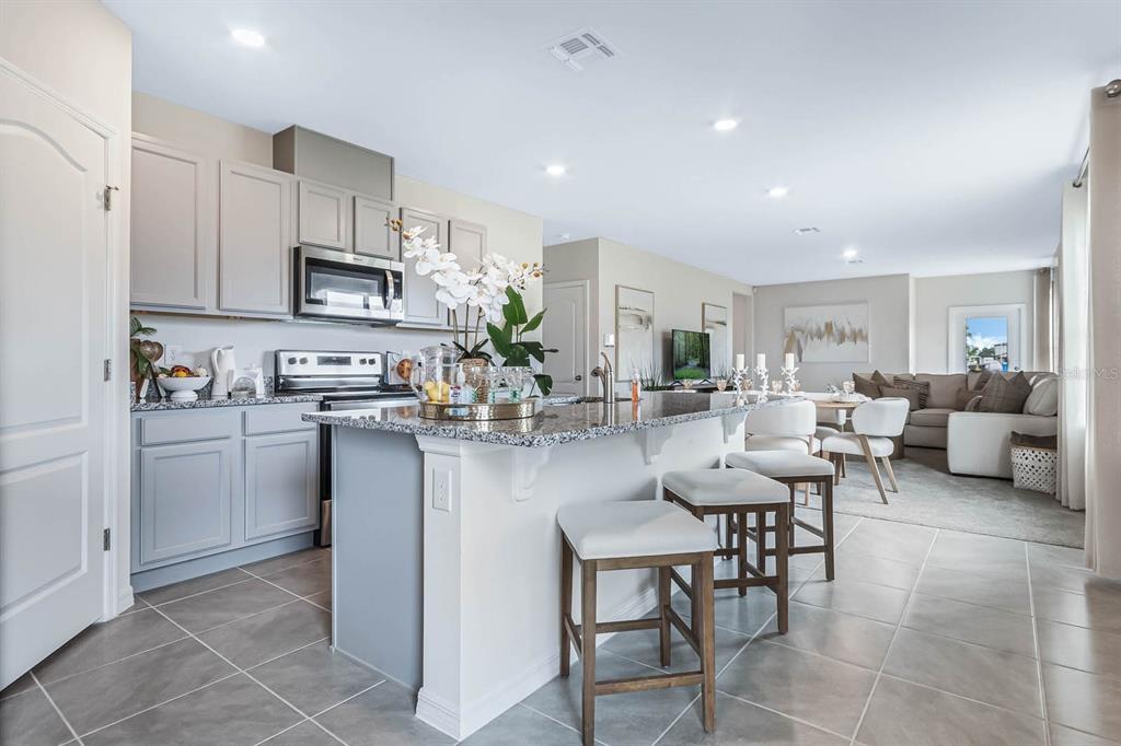 A kitchen with gray cabinets, granite countertops, and an island with bar stools — 1207 CUMBERLAND TRAIL DRIVE, HAINES CITY, FL