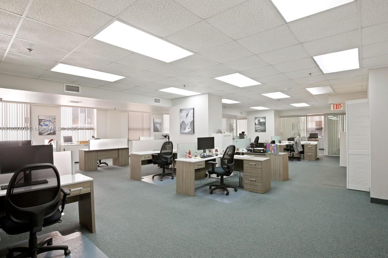 An office space features multiple desks, rolling chairs, drop ceilings, and large windows with blinds — 168 SE 1st St # 9, Miami FL 33131, MIAMI, FL