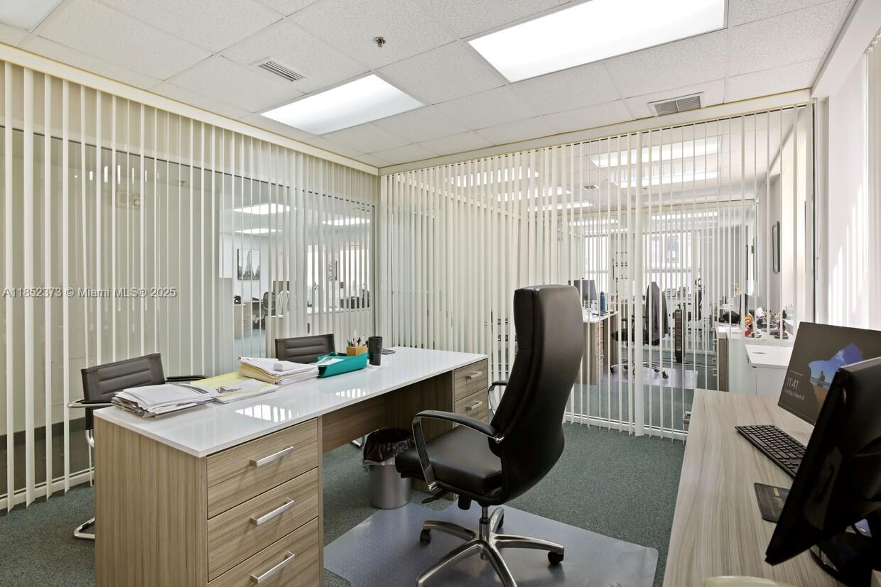 An office with a desk, black chairs, and vertical blinds separating it from another workspace — 168 SE 1st St # 9, Miami FL 33131, MIAMI, FL