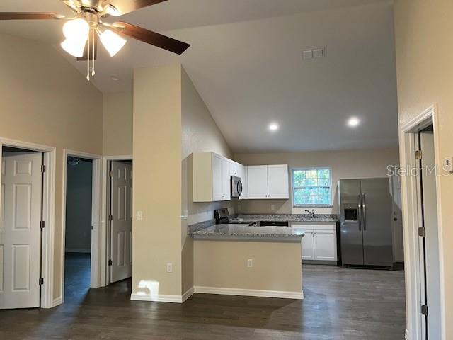 An open-concept kitchen features white cabinets, stainless steel appliances, and a breakfast bar — 4366 SE 138TH STREET, SUMMERFIELD, FL