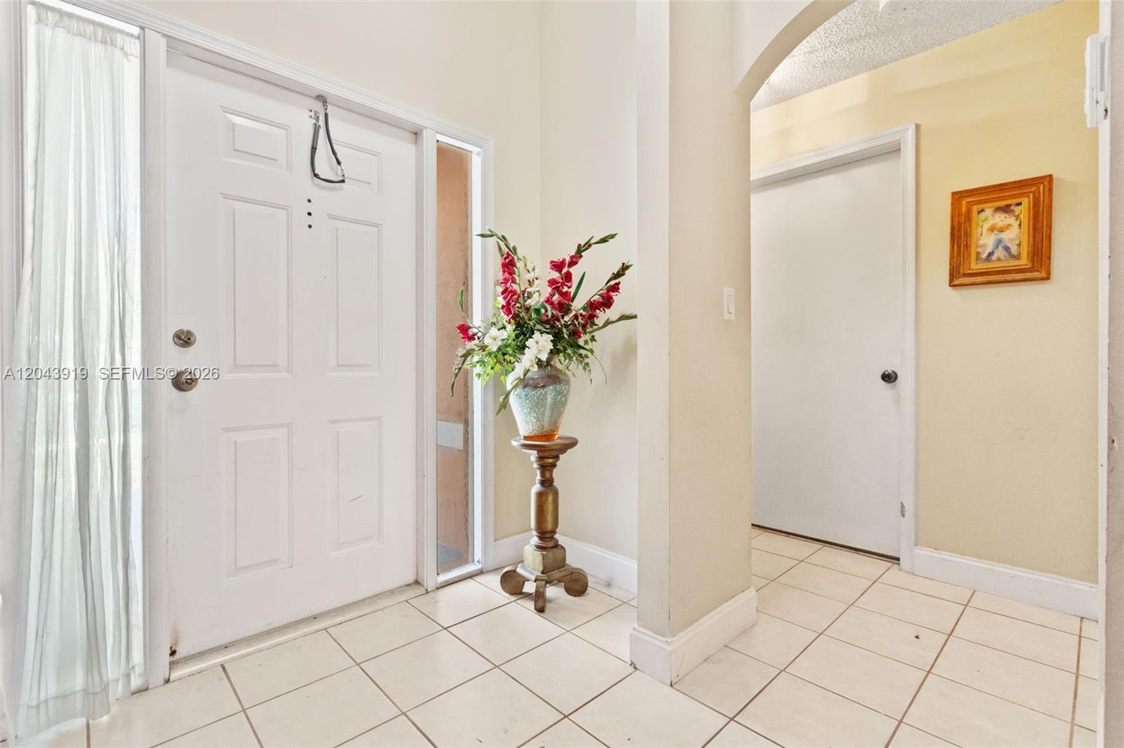 A tiled entryway features a white front door, a pedestal vase with flowers, and an archway — 4931 SW 152nd Ave, Miramar FL 33027, MIRAMAR, FL