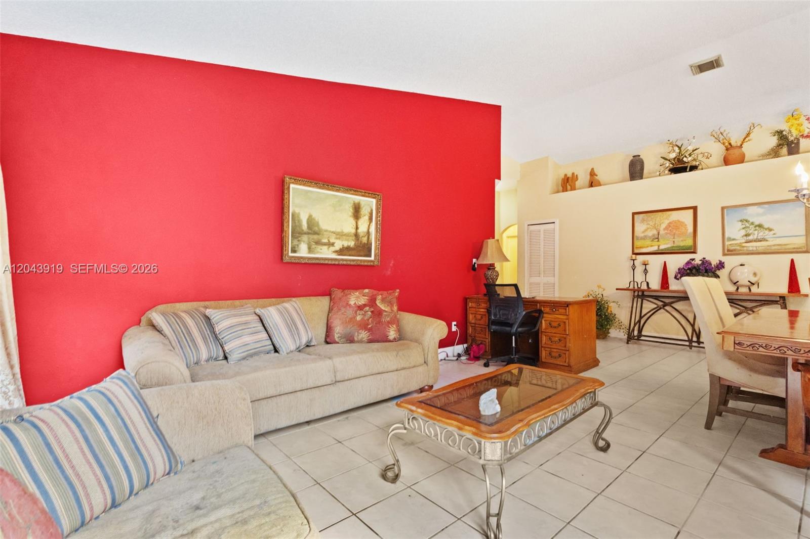 A living room features a bright red accent wall, beige sofa, and tile flooring — 4931 SW 152nd Ave, Miramar FL 33027, MIRAMAR, FL