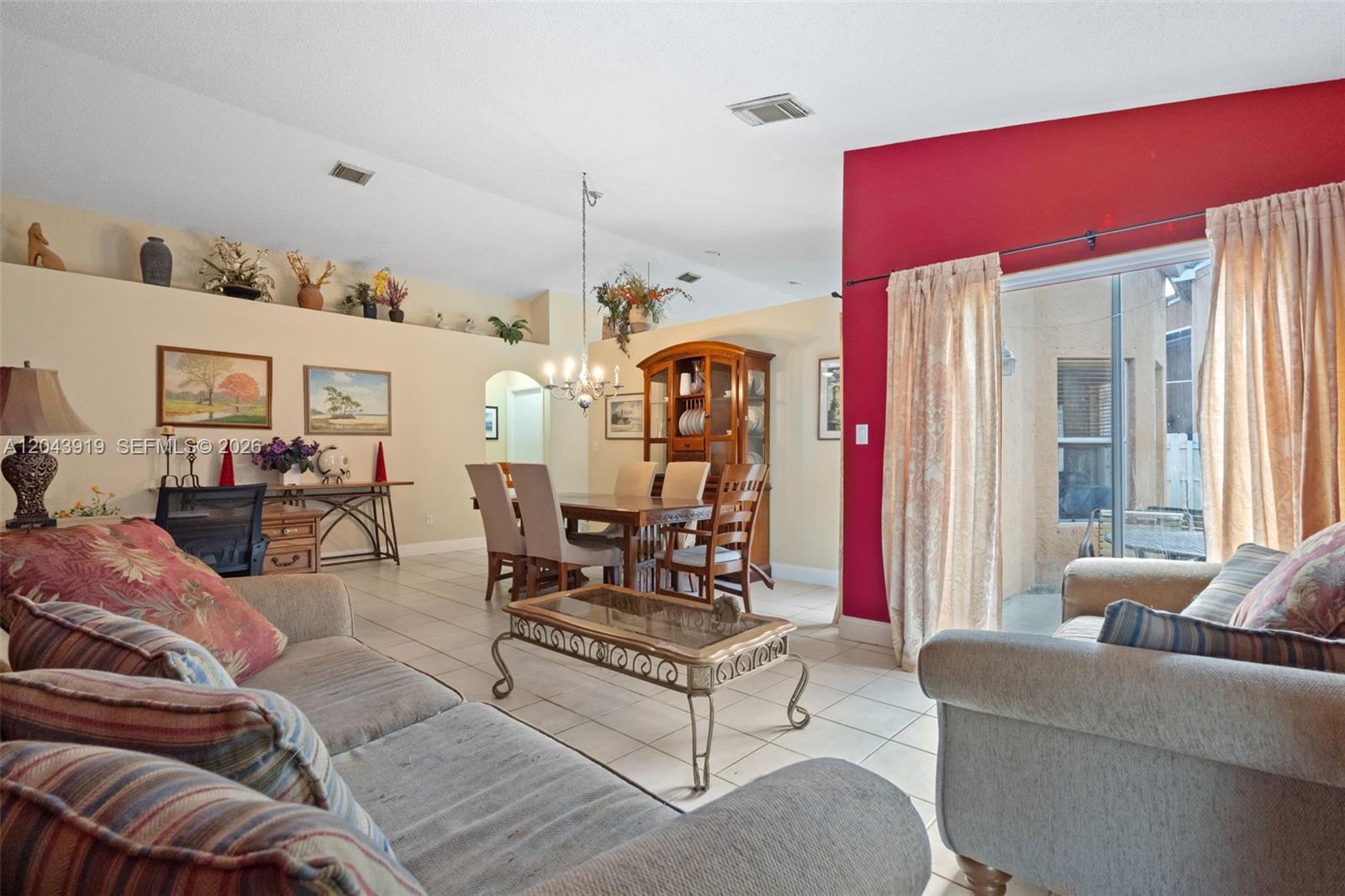 A living and dining room with tiled floors, a red accent wall, and vaulted ceilings — 4931 SW 152nd Ave, Miramar FL 33027, MIRAMAR, FL