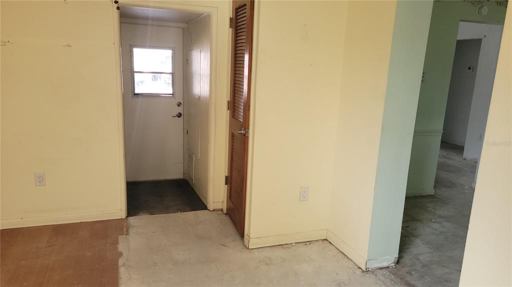 An interior view showing a yellow-walled room with a door, louvered closet, and doorway — 9850 LILY STREET N UNIT 117, PINELLAS PARK, FL