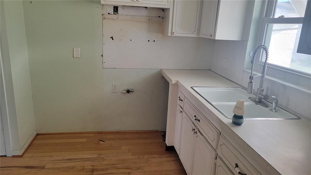 A kitchen with white cabinets, a double-basin sink, and an unfinished wall section — 9850 LILY STREET N UNIT 117, PINELLAS PARK, FL