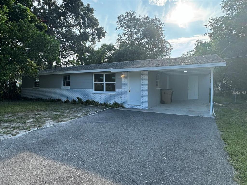 A single-story house with a gray and white exterior features a carport and driveway — 10601 N 52ND STREET, TEMPLE TERRACE, FL
