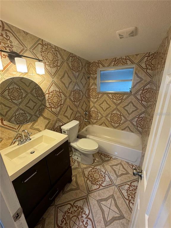 A bathroom features patterned wall and floor tiles, a dark vanity, and a white tub — 10601 N 52ND STREET, TEMPLE TERRACE, FL