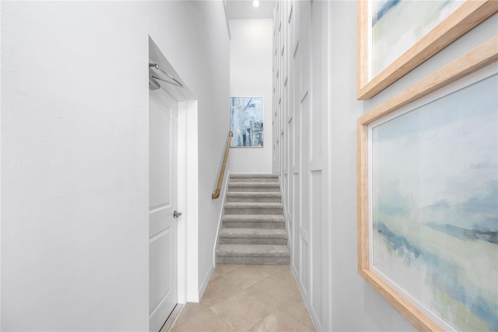 A staircase with carpeted steps and a wooden handrail leads up a hallway with wainscoting — 13001 PINK SAND COURT UNIT 203, VENICE, FL