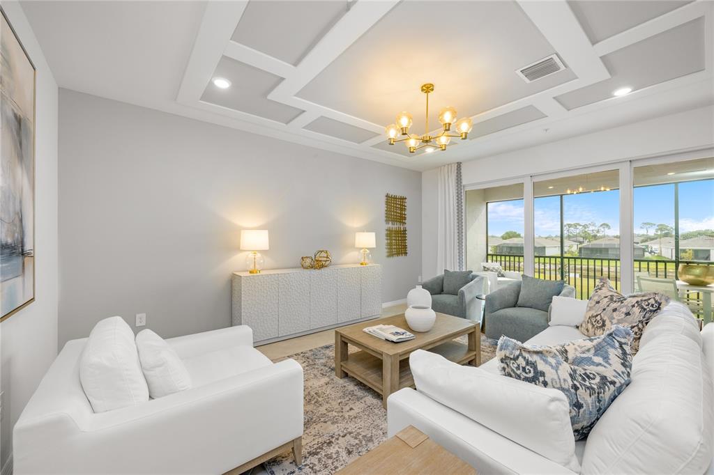 A living room features white sofas, a coffered ceiling, and a view of a lake — 13001 PINK SAND COURT UNIT 203, VENICE, FL