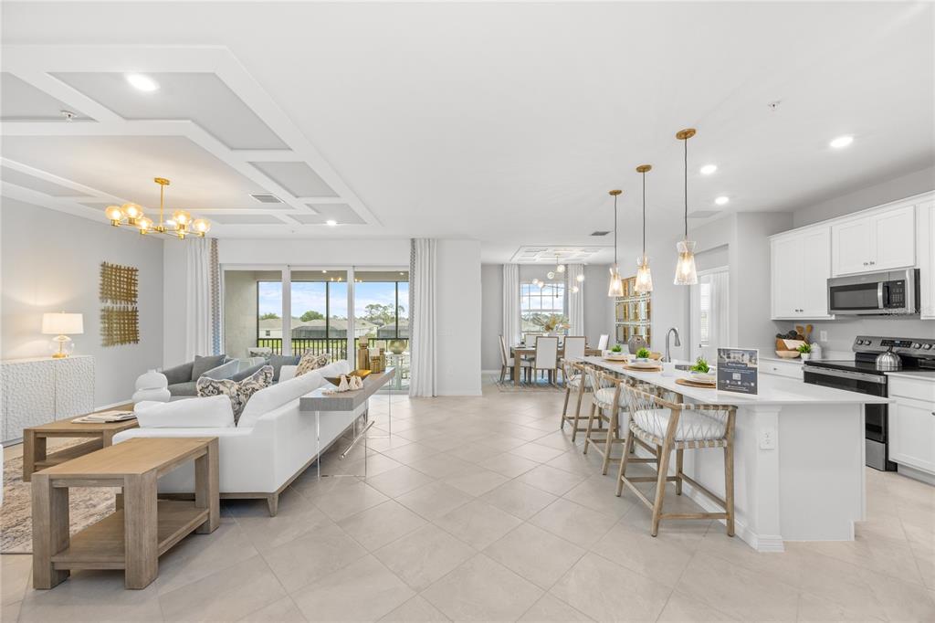 An open-concept living room, dining area, and kitchen with white cabinetry and tile flooring — 13001 PINK SAND COURT UNIT 203, VENICE, FL