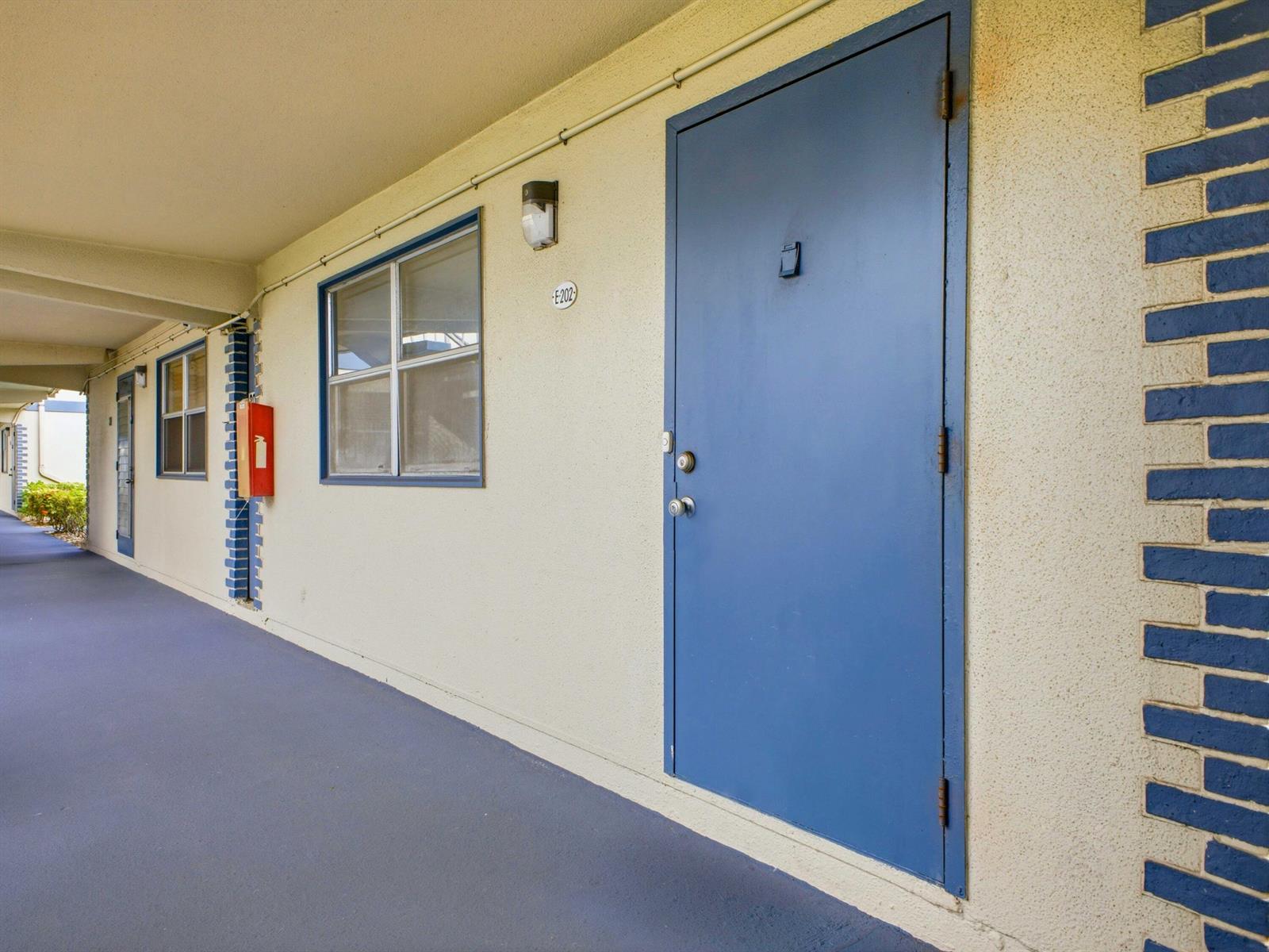A blue door and window are visible along a covered outdoor apartment building walkway — 202 Brittany E, Delray Beach FL 33446, DELRAY BEACH, FL