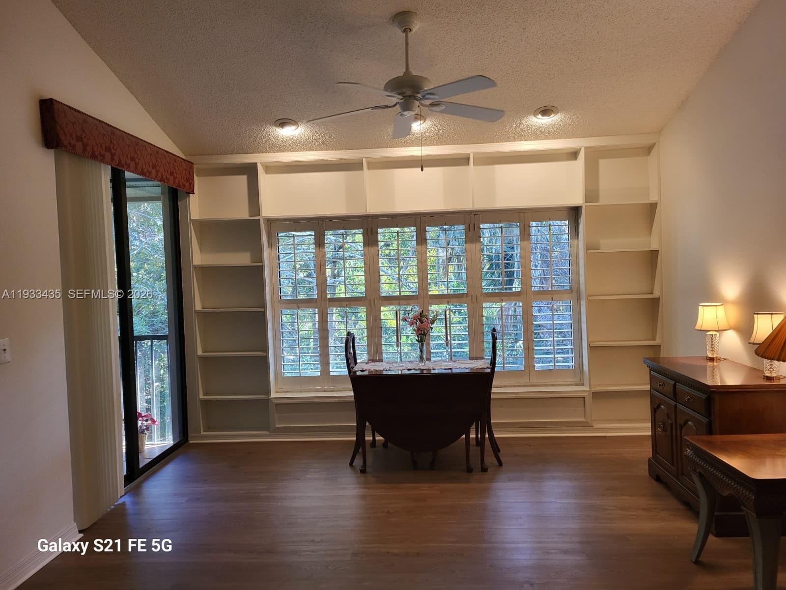 A dining area features built-in white shelving, plantation shutters, a ceiling fan, and wood flooring — 5200 SE Seascape Way # 201, Stuart FL 34997, STUART, FL