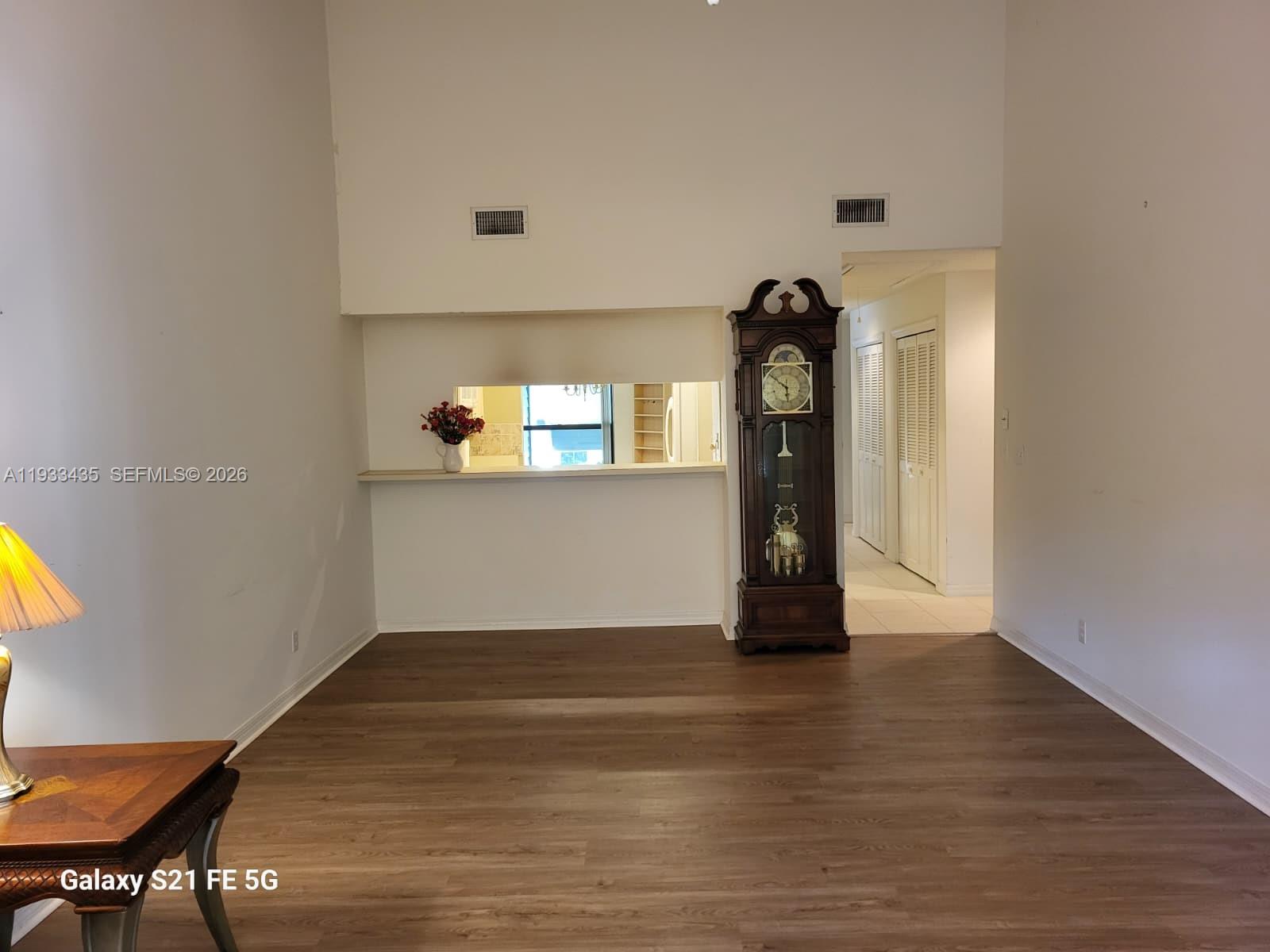 A room with wood-look flooring, a pass-through window, and a tall grandfather clock — 5200 SE Seascape Way # 201, Stuart FL 34997, STUART, FL