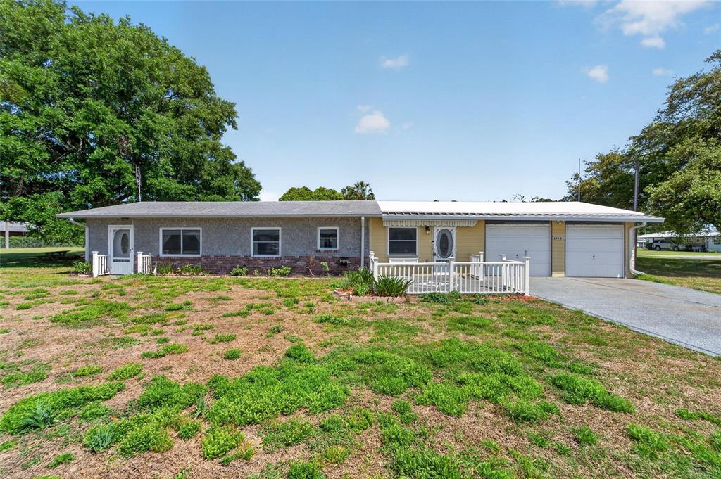 A single-story house with a gray and yellow exterior, a two-car garage, and a lawn — 39407 ROCKFORD AVENUE, ZEPHYRHILLS, FL