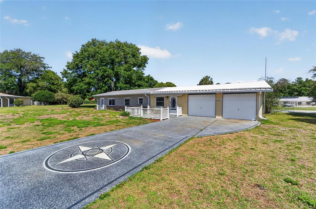 A single-story house with a two-car garage and a star design on the driveway — 39407 ROCKFORD AVENUE, ZEPHYRHILLS, FL