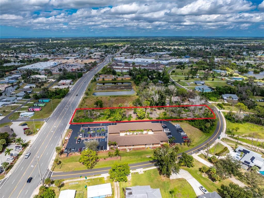 An aerial view shows a rectangular plot of land outlined in red near a commercial building — 1781 PLACIDA ROAD, ENGLEWOOD, FL