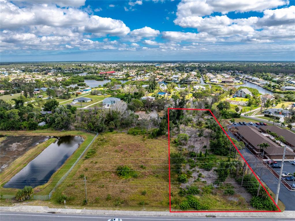 An aerial view shows a vacant, rectangular lot outlined in red next to a commercial building — 1781 PLACIDA ROAD, ENGLEWOOD, FL