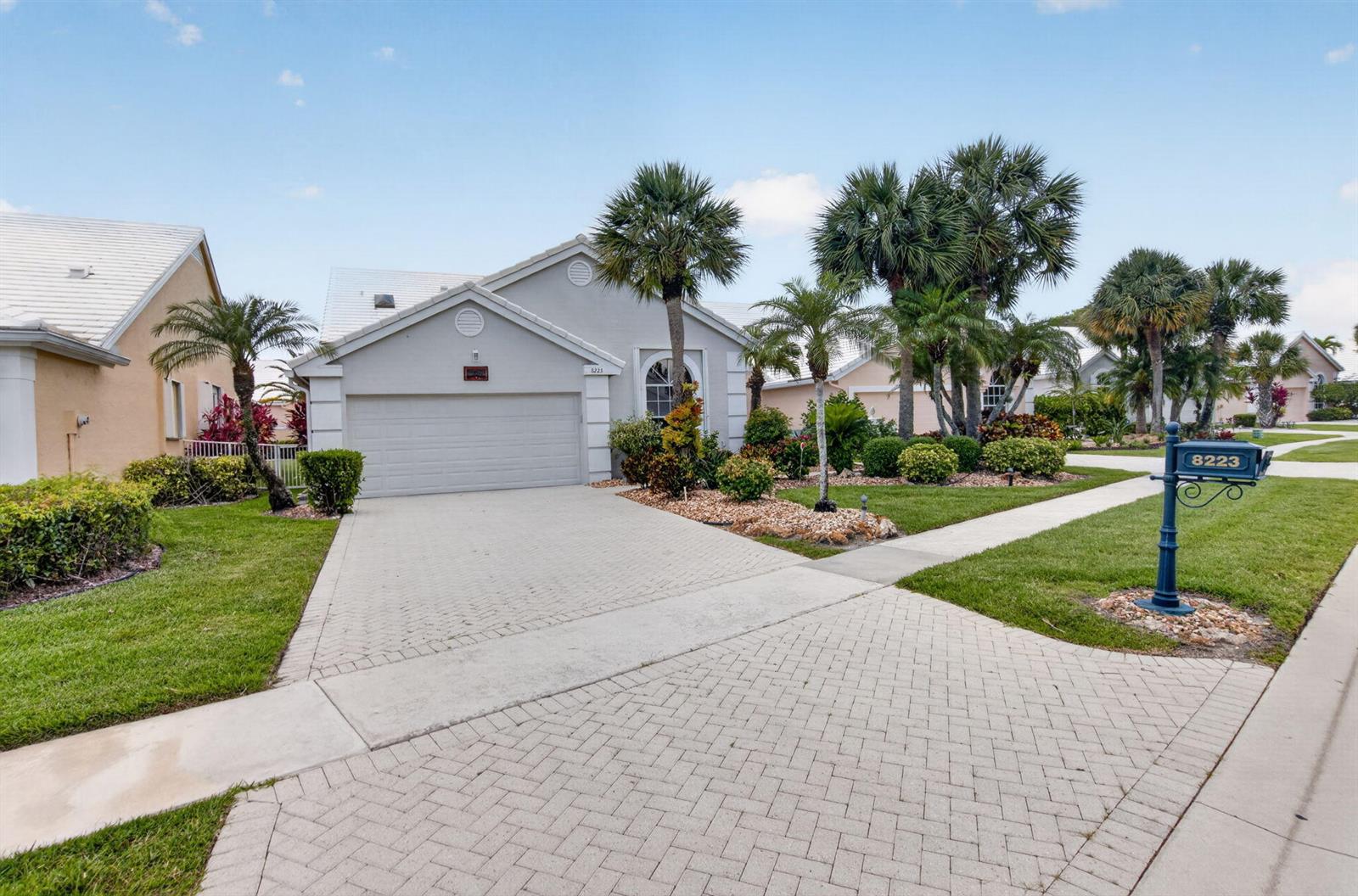 A single-story house with a paved driveway, a two-car garage, and palm trees in front — 8223 Horseshoe Bay Road, Boynton Beach FL 33472, BOYNTON BEACH, FL
