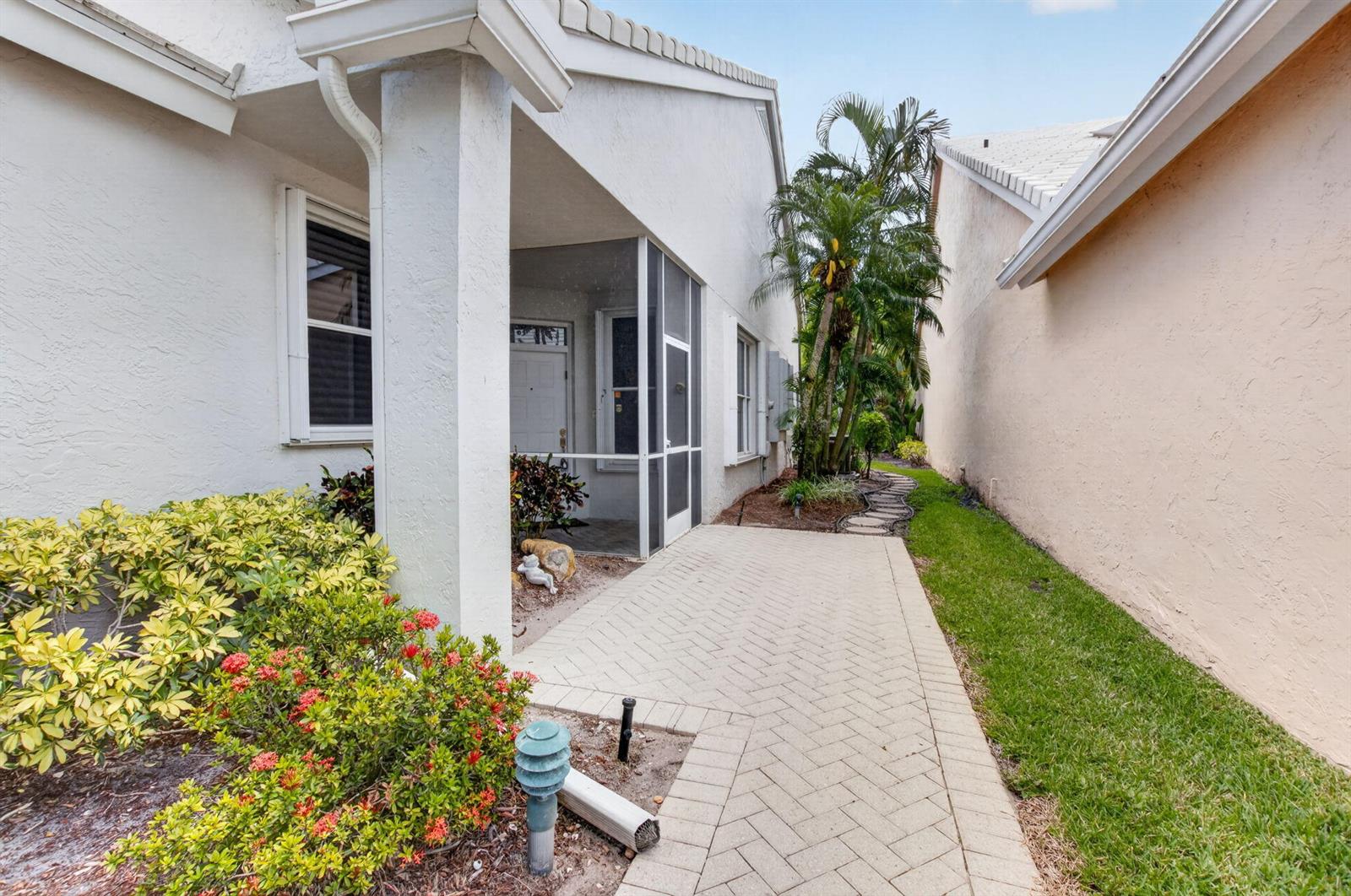 A paved walkway leads to a screened-in porch between two suburban houses with landscaping — 8223 Horseshoe Bay Road, Boynton Beach FL 33472, BOYNTON BEACH, FL