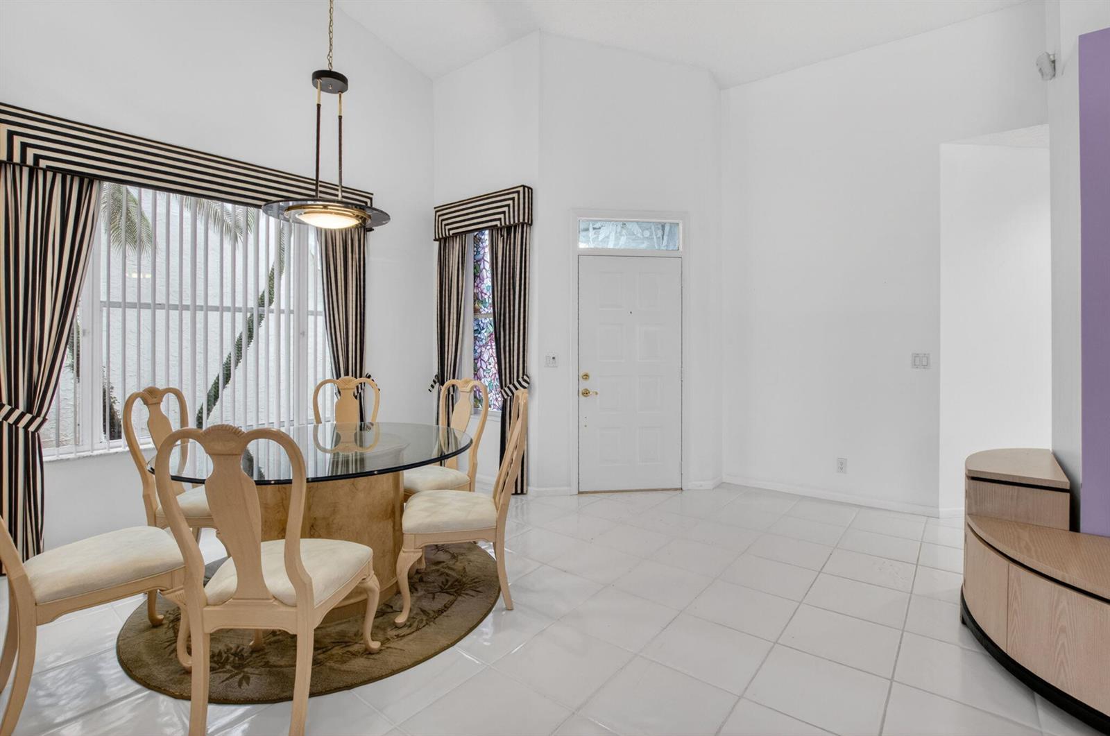 A dining area features a glass-topped table, light-colored chairs, tile flooring, and striped window treatments — 8223 Horseshoe Bay Road, Boynton Beach FL 33472, BOYNTON BEACH, FL