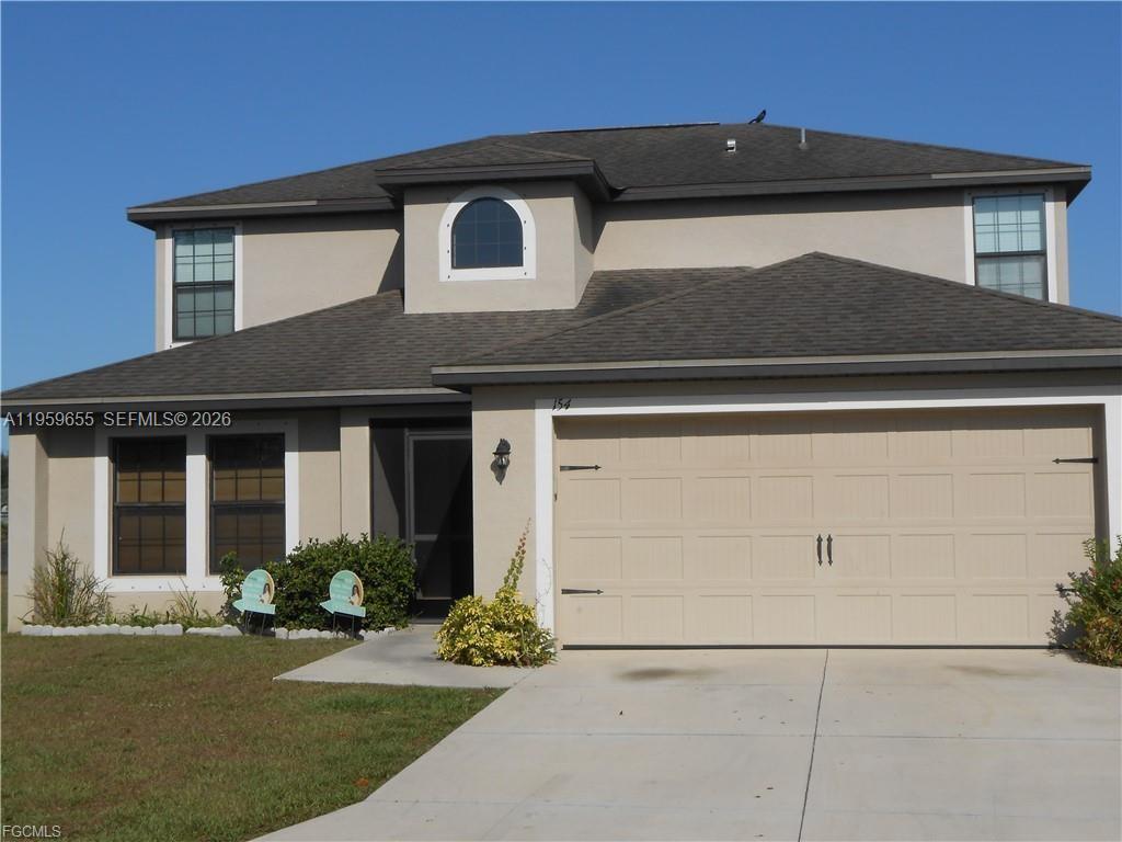 A two-story house with a beige stucco exterior, a two-car garage, and a shingled roof — 154 Shadowview Ct., Lehigh Acres FL 33974, LEHIGH ACRES, FL