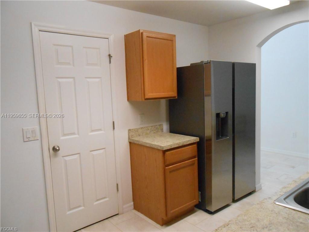 A kitchen features a stainless steel refrigerator, wood cabinets, and a beige countertop — 154 Shadowview Ct., Lehigh Acres FL 33974, LEHIGH ACRES, FL